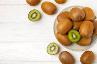 Ahşap arka planda Kivi. Masada tam meyve ve dilimler halinde yeşil kivi var. Taze sulu kivi. Tropik meyve. Organik meyve. Sağlıklı beslenme. Mesaj için yer var. Boşluğu kopyala.