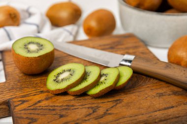 Ahşap arka planda Kivi. Masada tam meyve ve dilimler halinde yeşil kivi var. Taze sulu kivi. Tropik meyve. Organik meyve. Sağlıklı beslenme. Mesaj için yer var. Boşluğu kopyala.