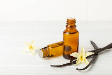 Bir şişe vanilya yağı ve desenli arka planda vanilya çiçeği. aromatik vanilyalı fasulye. Vanilya özü. Spa konsepti. Güzellik ve özen. Mesaj için yer. Boşluğu kopyala.