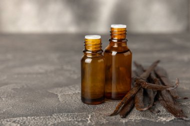 Bir şişe vanilya yağı ve desenli arka planda vanilya çiçeği. aromatik vanilyalı fasulye. Vanilya özü. Spa konsepti. Güzellik ve özen. Mesaj için yer. Boşluğu kopyala.