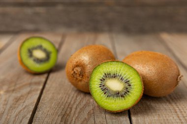 Ahşap arka planda Kivi. Masada tam meyve ve dilimler halinde yeşil kivi var. Taze sulu kivi. Tropik meyve. Organik meyve. Sağlıklı beslenme. Mesaj için yer var. Boşluğu kopyala.
