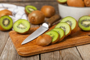 Ahşap arka planda Kivi. Masada tam meyve ve dilimler halinde yeşil kivi var. Taze sulu kivi. Tropik meyve. Organik meyve. Sağlıklı beslenme. Mesaj için yer var. Boşluğu kopyala.