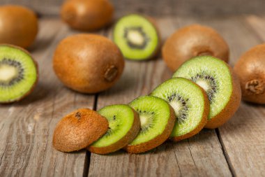 Ahşap arka planda Kivi. Masada tam meyve ve dilimler halinde yeşil kivi var. Taze sulu kivi. Tropik meyve. Organik meyve. Sağlıklı beslenme. Mesaj için yer var. Boşluğu kopyala.