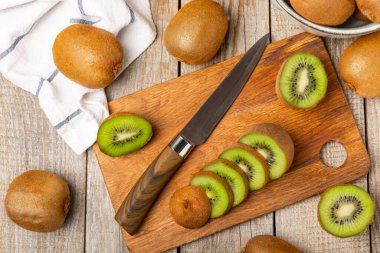 Ahşap arka planda Kivi. Masada tam meyve ve dilimler halinde yeşil kivi var. Taze sulu kivi. Tropik meyve. Organik meyve. Sağlıklı beslenme. Mesaj için yer var. Boşluğu kopyala.