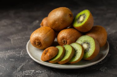 Ahşap arka planda Kivi. Masada tam meyve ve dilimler halinde yeşil kivi var. Taze sulu kivi. Tropik meyve. Organik meyve. Sağlıklı beslenme. Mesaj için yer var. Boşluğu kopyala.