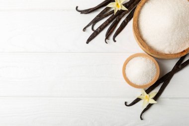 Aromatik vanilya şekeri. Vanilya kabukları. Vanilya çubukları, esmer ve beyaz şeker dokulu arka planda bir kasede. Vanilya çiçekleri, baharatlar ve tatlı ve pişirme için bitkiler. Mesaj için yer var. Boşluğu kopyala