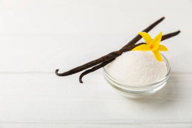 Aromatik vanilya şekeri. Vanilya kabukları. Vanilya çubukları, esmer ve beyaz şeker dokulu arka planda bir kasede. Vanilya çiçekleri, baharatlar ve tatlı ve pişirme için bitkiler. Mesaj için yer var. Boşluğu kopyala