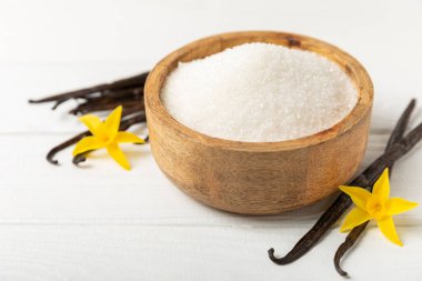 Aromatik vanilya şekeri. Vanilya kabukları. Vanilya çubukları, esmer ve beyaz şeker dokulu arka planda bir kasede. Vanilya çiçekleri, baharatlar ve tatlı ve pişirme için bitkiler. Mesaj için yer var. Boşluğu kopyala