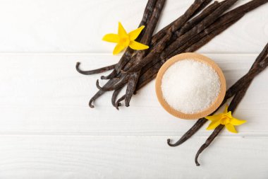 Aromatik vanilya şekeri. Vanilya kabukları. Vanilya çubukları, esmer ve beyaz şeker dokulu arka planda bir kasede. Vanilya çiçekleri, baharatlar ve tatlı ve pişirme için bitkiler. Mesaj için yer var. Boşluğu kopyala