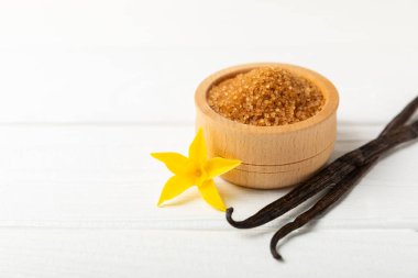 Aromatik vanilya şekeri. Vanilya kabukları. Vanilya çubukları, esmer ve beyaz şeker dokulu arka planda bir kasede. Vanilya çiçekleri, baharatlar ve tatlı ve pişirme için bitkiler. Mesaj için yer var. Boşluğu kopyala