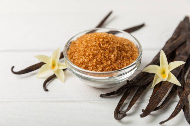 Aromatik vanilya şekeri. Vanilya kabukları. Vanilya çubukları, esmer ve beyaz şeker dokulu arka planda bir kasede. Vanilya çiçekleri, baharatlar ve tatlı ve pişirme için bitkiler. Mesaj için yer var. Boşluğu kopyala