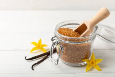 Aromatik vanilya şekeri. Vanilya kabukları. Vanilya çubukları, esmer ve beyaz şeker dokulu arka planda bir kasede. Vanilya çiçekleri, baharatlar ve tatlı ve pişirme için bitkiler. Mesaj için yer var. Boşluğu kopyala