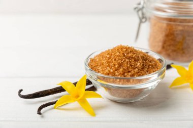 Aromatik vanilya şekeri. Vanilya kabukları. Vanilya çubukları, esmer ve beyaz şeker dokulu arka planda bir kasede. Vanilya çiçekleri, baharatlar ve tatlı ve pişirme için bitkiler. Mesaj için yer var. Boşluğu kopyala