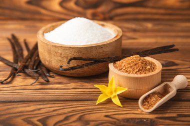 Aromatik vanilya şekeri. Vanilya kabukları. Vanilya çubukları, esmer ve beyaz şeker dokulu arka planda bir kasede. Vanilya çiçekleri, baharatlar ve tatlı ve pişirme için bitkiler. Mesaj için yer var. Boşluğu kopyala