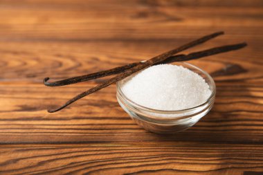 Aromatik vanilya şekeri. Vanilya kabukları. Vanilya çubukları, esmer ve beyaz şeker dokulu arka planda bir kasede. Vanilya çiçekleri, baharatlar ve tatlı ve pişirme için bitkiler. Mesaj için yer var. Boşluğu kopyala