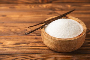 Aromatik vanilya şekeri. Vanilya kabukları. Vanilya çubukları, esmer ve beyaz şeker dokulu arka planda bir kasede. Vanilya çiçekleri, baharatlar ve tatlı ve pişirme için bitkiler. Mesaj için yer var. Boşluğu kopyala