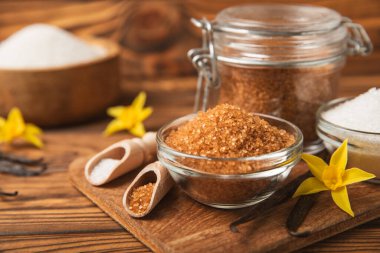 Aromatik vanilya şekeri. Vanilya kabukları. Vanilya çubukları, esmer ve beyaz şeker dokulu arka planda bir kasede. Vanilya çiçekleri, baharatlar ve tatlı ve pişirme için bitkiler. Mesaj için yer var. Boşluğu kopyala