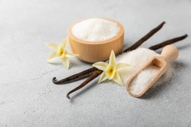 Aromatik vanilya şekeri. Vanilya kabukları. Vanilya çubukları, esmer ve beyaz şeker dokulu arka planda bir kasede. Vanilya çiçekleri, baharatlar ve tatlı ve pişirme için bitkiler. Mesaj için yer var. Boşluğu kopyala