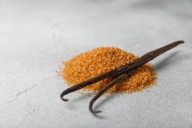 Aromatik vanilya şekeri. Vanilya kabukları. Vanilya çubukları, esmer ve beyaz şeker dokulu arka planda bir kasede. Vanilya çiçekleri, baharatlar ve tatlı ve pişirme için bitkiler. Mesaj için yer var. Boşluğu kopyala