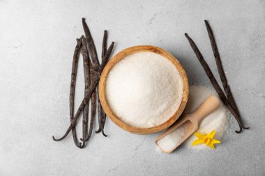 Aromatik vanilya şekeri. Vanilya kabukları. Vanilya çubukları, esmer ve beyaz şeker dokulu arka planda bir kasede. Vanilya çiçekleri, baharatlar ve tatlı ve pişirme için bitkiler. Mesaj için yer var. Boşluğu kopyala