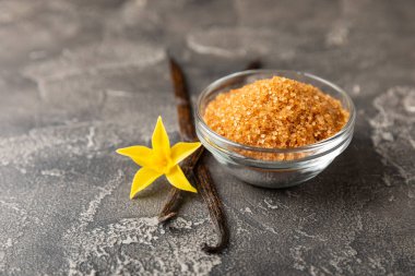 Aromatik vanilya şekeri. Vanilya kabukları. Vanilya çubukları, esmer ve beyaz şeker dokulu arka planda bir kasede. Vanilya çiçekleri, baharatlar ve tatlı ve pişirme için bitkiler. Mesaj için yer var. Boşluğu kopyala