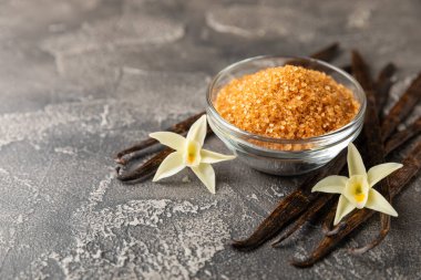 Aromatik vanilya şekeri. Vanilya kabukları. Vanilya çubukları, esmer ve beyaz şeker dokulu arka planda bir kasede. Vanilya çiçekleri, baharatlar ve tatlı ve pişirme için bitkiler. Mesaj için yer var. Boşluğu kopyala