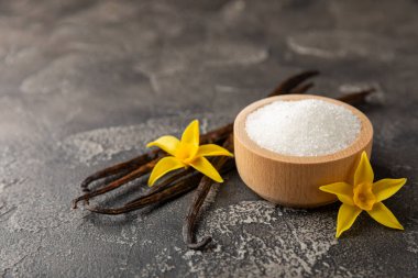 Aromatik vanilya şekeri. Vanilya kabukları. Vanilya çubukları, esmer ve beyaz şeker dokulu arka planda bir kasede. Vanilya çiçekleri, baharatlar ve tatlı ve pişirme için bitkiler. Mesaj için yer var. Boşluğu kopyala