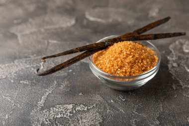 Aromatik vanilya şekeri. Vanilya kabukları. Vanilya çubukları, esmer ve beyaz şeker dokulu arka planda bir kasede. Vanilya çiçekleri, baharatlar ve tatlı ve pişirme için bitkiler. Mesaj için yer var. Boşluğu kopyala