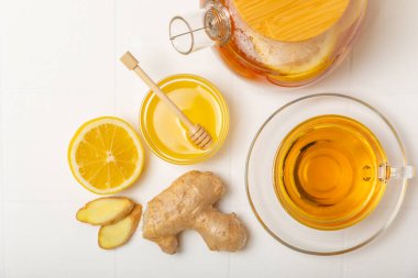 Tahta zemin üzerinde zencefil kökü dilimleri olan bir fincan sıcak zencefil çayı. Isıtıcı içecek. Alternatif tıp. Ballı, limonlu, zencefilli ve naneli çay. Mesaj için yer var. Boşluğu kopyala