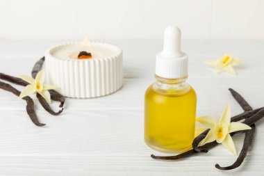 Bir şişe vanilya yağı ve desenli arka planda vanilya çiçeği. aromatik vanilyalı fasulye. Vanilya özü. Spa konsepti. Güzellik ve özen. Mesaj için yer. Boşluğu kopyala.