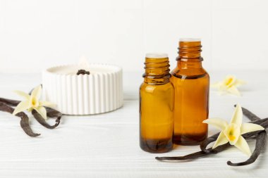 Bir şişe vanilya yağı ve desenli arka planda vanilya çiçeği. aromatik vanilyalı fasulye. Vanilya özü. Spa konsepti. Güzellik ve özen. Mesaj için yer. Boşluğu kopyala.