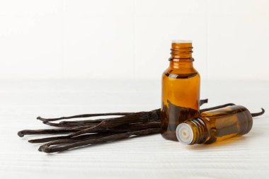 Bir şişe vanilya yağı ve desenli arka planda vanilya çiçeği. aromatik vanilyalı fasulye. Vanilya özü. Spa konsepti. Güzellik ve özen. Mesaj için yer. Boşluğu kopyala.