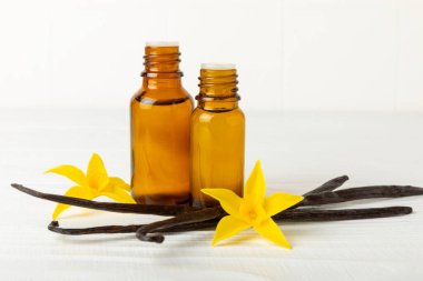 Bir şişe vanilya yağı ve desenli arka planda vanilya çiçeği. aromatik vanilyalı fasulye. Vanilya özü. Spa konsepti. Güzellik ve özen. Mesaj için yer. Boşluğu kopyala.