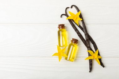 Bir şişe vanilya yağı ve desenli arka planda vanilya çiçeği. aromatik vanilyalı fasulye. Vanilya özü. Spa konsepti. Güzellik ve özen. Mesaj için yer. Boşluğu kopyala.