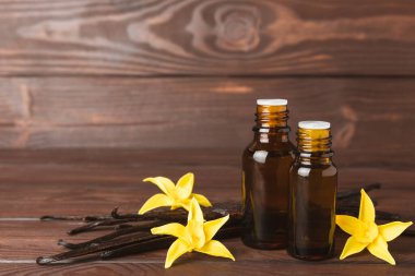 Bir şişe vanilya yağı ve desenli arka planda vanilya çiçeği. aromatik vanilyalı fasulye. Vanilya özü. Spa konsepti. Güzellik ve özen. Mesaj için yer. Boşluğu kopyala.