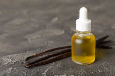 Bir şişe vanilya yağı ve desenli arka planda vanilya çiçeği. aromatik vanilyalı fasulye. Vanilya özü. Spa konsepti. Güzellik ve özen. Mesaj için yer. Boşluğu kopyala.