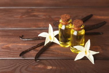 Bir şişe vanilya yağı ve desenli arka planda vanilya çiçeği. aromatik vanilyalı fasulye. Vanilya özü. Spa konsepti. Güzellik ve özen. Mesaj için yer. Boşluğu kopyala.