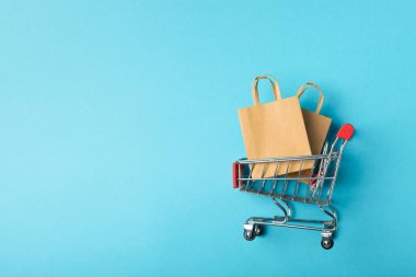 Çevrimiçi alışveriş kavramı. Karton kutu ve parlak renkli bir arka planda tramvayda alışveriş poşetleri. Alışveriş sepeti. İnternetten bilgisayar, tablet, telefon ve kredi kartı kullanarak alışveriş. Eve teslim.