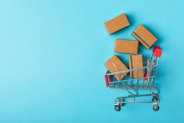 Çevrimiçi alışveriş kavramı. Karton kutu ve parlak renkli bir arka planda tramvayda alışveriş poşetleri. Alışveriş sepeti. İnternetten bilgisayar, tablet, telefon ve kredi kartı kullanarak alışveriş. Eve teslim.