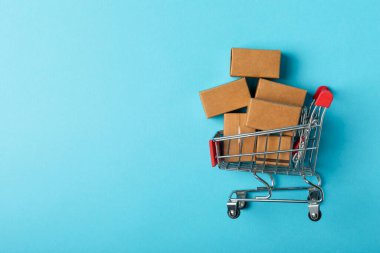 Çevrimiçi alışveriş kavramı. Karton kutu ve parlak renkli bir arka planda tramvayda alışveriş poşetleri. Alışveriş sepeti. İnternetten bilgisayar, tablet, telefon ve kredi kartı kullanarak alışveriş. Eve teslim.