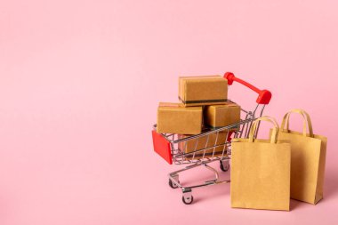 Çevrimiçi alışveriş kavramı. Karton kutu ve parlak renkli bir arka planda tramvayda alışveriş poşetleri. Alışveriş sepeti. İnternetten bilgisayar, tablet, telefon ve kredi kartı kullanarak alışveriş. Eve teslim.