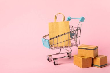 Çevrimiçi alışveriş kavramı. Karton kutu ve parlak renkli bir arka planda tramvayda alışveriş poşetleri. Alışveriş sepeti. İnternetten bilgisayar, tablet, telefon ve kredi kartı kullanarak alışveriş. Eve teslim.