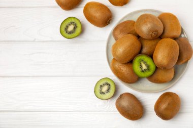 Ahşap arka planda Kivi. Masada tam meyve ve dilimler halinde yeşil kivi var. Taze sulu kivi. Tropik meyve. Organik meyve. Sağlıklı beslenme. Mesaj için yer var. Boşluğu kopyala