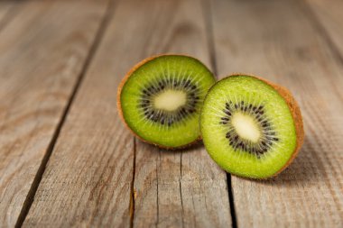 Ahşap arka planda Kivi. Masada tam meyve ve dilimler halinde yeşil kivi var. Taze sulu kivi. Tropik meyve. Organik meyve. Sağlıklı beslenme. Mesaj için yer var. Boşluğu kopyala