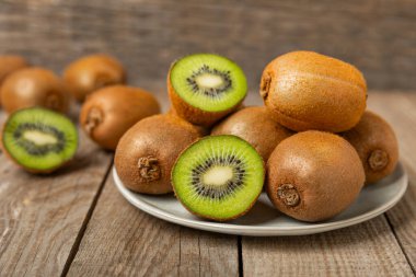 Ahşap arka planda Kivi. Masada tam meyve ve dilimler halinde yeşil kivi var. Taze sulu kivi. Tropik meyve. Organik meyve. Sağlıklı beslenme. Mesaj için yer var. Boşluğu kopyala