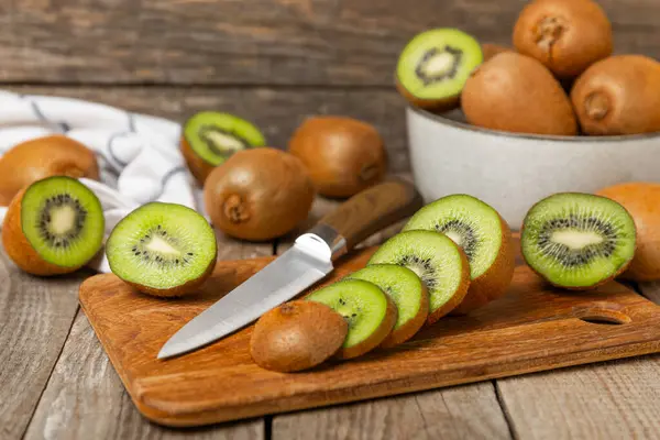 Ahşap arka planda Kivi. Masada tam meyve ve dilimler halinde yeşil kivi var. Taze sulu kivi. Tropik meyve. Organik meyve. Sağlıklı beslenme. Mesaj için yer var. Boşluğu kopyala