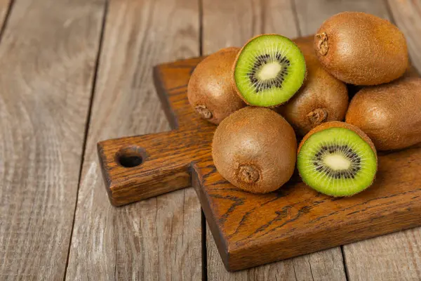Ahşap arka planda Kivi. Masada tam meyve ve dilimler halinde yeşil kivi var. Taze sulu kivi. Tropik meyve. Organik meyve. Sağlıklı beslenme. Mesaj için yer var. Boşluğu kopyala