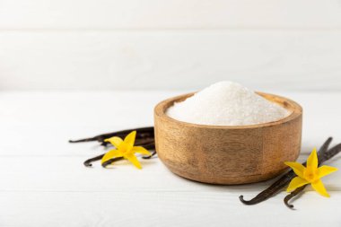Aromatik vanilya şekeri. Vanilya kabukları. Vanilya çubukları, esmer ve beyaz şeker dokulu arka planda bir kasede. Vanilya çiçekleri, baharatlar ve tatlı ve pişirme için bitkiler. Mesaj için yer var. Boşluğu kopyala