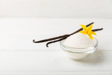 Aromatik vanilya şekeri. Vanilya kabukları. Vanilya çubukları, esmer ve beyaz şeker dokulu arka planda bir kasede. Vanilya çiçekleri, baharatlar ve tatlı ve pişirme için bitkiler. Mesaj için yer var. Boşluğu kopyala