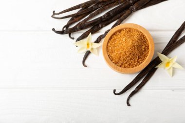 Aromatik vanilya şekeri. Vanilya kabukları. Vanilya çubukları, esmer ve beyaz şeker dokulu arka planda bir kasede. Vanilya çiçekleri, baharatlar ve tatlı ve pişirme için bitkiler. Mesaj için yer var. Boşluğu kopyala